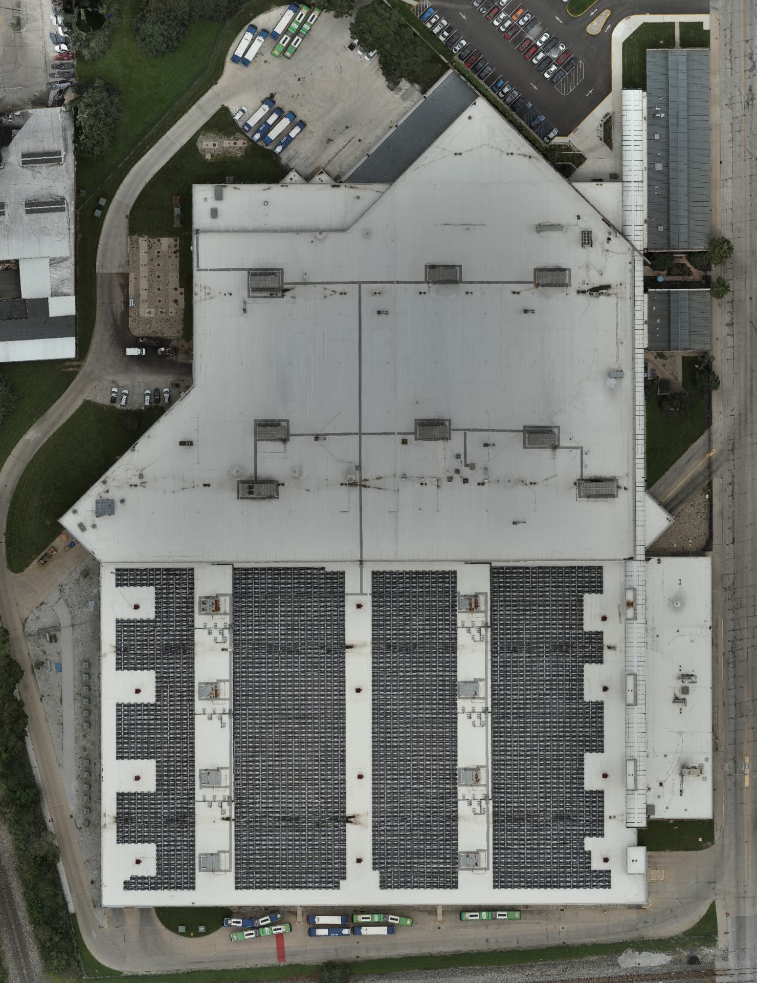 High-resolution RGB orthomosaic of a large facility roof with solar arrays, equipment and surrounding grounds